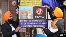 "Бұл жерде TikTok қолдануға тыйым салынады" деген жазуы бар баннерді іліп жатқан адамдар. Амритсар, Пенджаб штаты, Үндістан. 10 ақпан 2020 жыл.