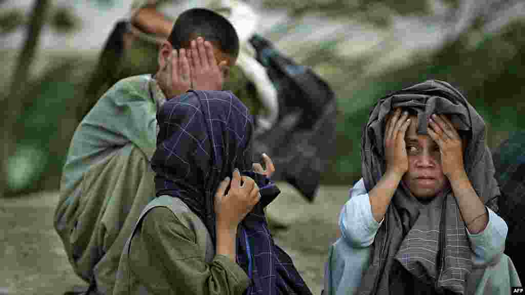 Afghan villagers hide their faces as a patrol by U.S. Army soldiers passes through the village of Qalacha in Kandahar. (AFP/Tony Karumba)