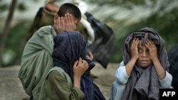 FILE: Villagers hide their faces during a security sweep in Qalacha village in Kandahar province.