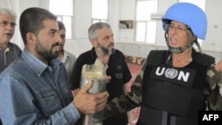 A Syrian resident shows a shell to a United Nations observer in the Talbisah area in Homs on June 11.