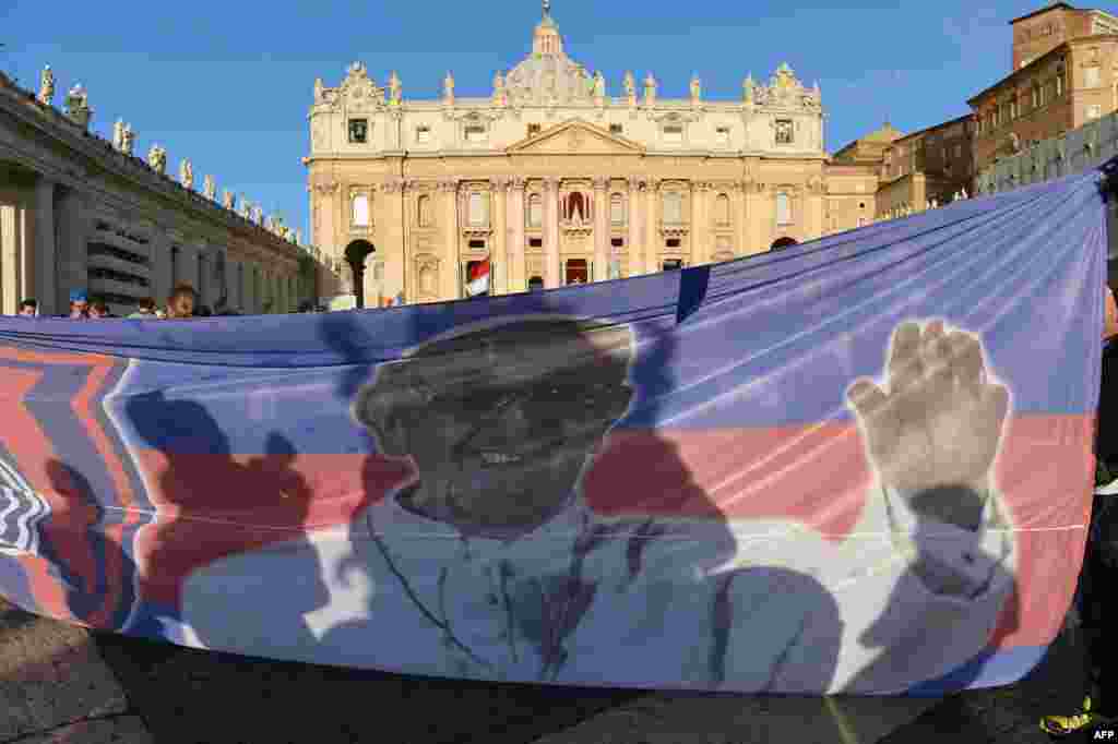 Roman Catholic faithful hold a banner of Pope Francis in St. Peter&#39;s Square ahead of his inauguration Mass.