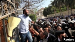 Egyptian police try to remove an Islamist protester chanting slogans from the fence of the Iranian ambassador's house during a protest against Iran in Cairo on April 5. 
