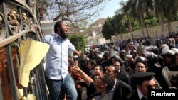 Egyptian police try to remove an Islamist protester chanting slogans from the fence of the Iranian ambassador's house during a protest against Iran in Cairo on April 5.