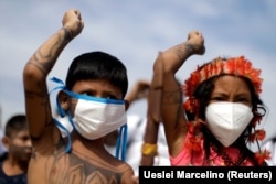 A munduruku őslakos törzshöz tartozó gyerekek védőmaszkban vesznek részt az őslakosok földjein történő bányászat elleni tiltakozáson Brazíliában, 2021. április 20-án