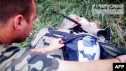 A screen grab taken from the News Corp video shows a Russian-backed rebel looking through the personal belongs of passengers at the site of downed Malaysia Airlines Flight MH17 shortly after it crashed.