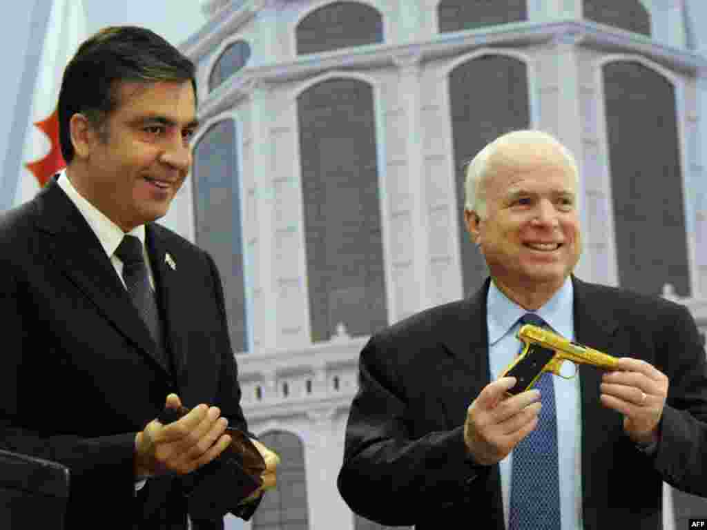 Gürcüstan prezidenti Mikheil Saakashvili (solda) ABŞ senatoru Con Makkeynə qızıl dəstəkli tapança bağışlayır. 2010&nbsp;