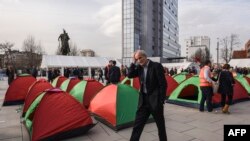  A man walks past tents set up by supporters of opposition parties in front of the Kosovo government building in Pristina on February 23