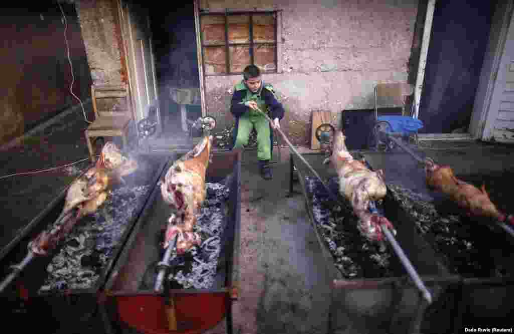 An ethnic Serb boy roasts lamb and pig for a traditional Orthodox Christmas meal in front of his home in the village of Vojkovici, near the capital, Sarajevo. (Reuters/Dado Ruvic)
