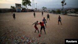 Падлеткі гуляюць у футбол на пляжы ў Порт-о-Прэнсе, архіўнае фота