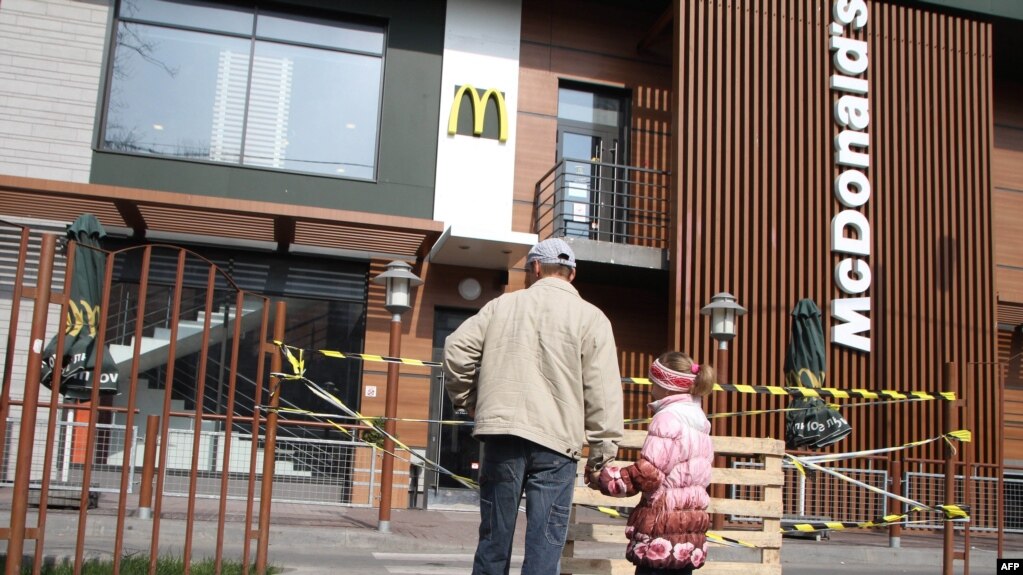 Мужчина с ребенком смотрят на закрытое помещение McDonald’s в Симферополе, 4 апреля 2014 года