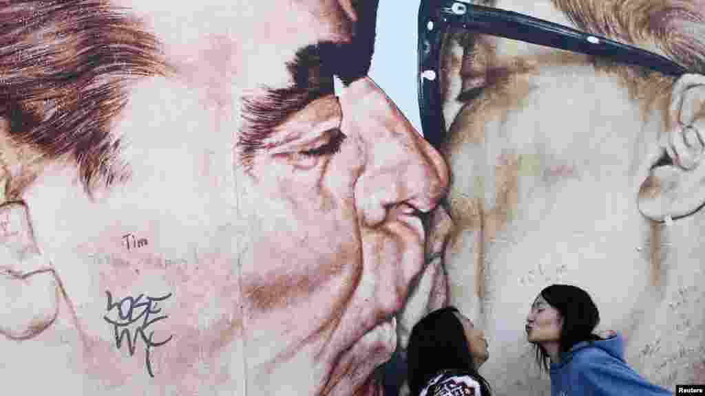 Chinese women pose in front of a painting on the Berlin Wall depicting Erich Honecker and Leonid Brezhnev&nbsp; on October 3, the 22nd anniversary of Germany&#39;s reunification. (Reuters/Lisi Niesner)