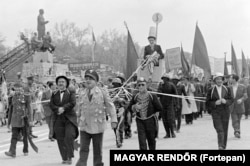 Uncle Sam (on throne) drives a parody parade past Budapest’s Stalin monument in 1954. The monument would soon be torn down by crowds during what became known as the Hungarian Revolution.