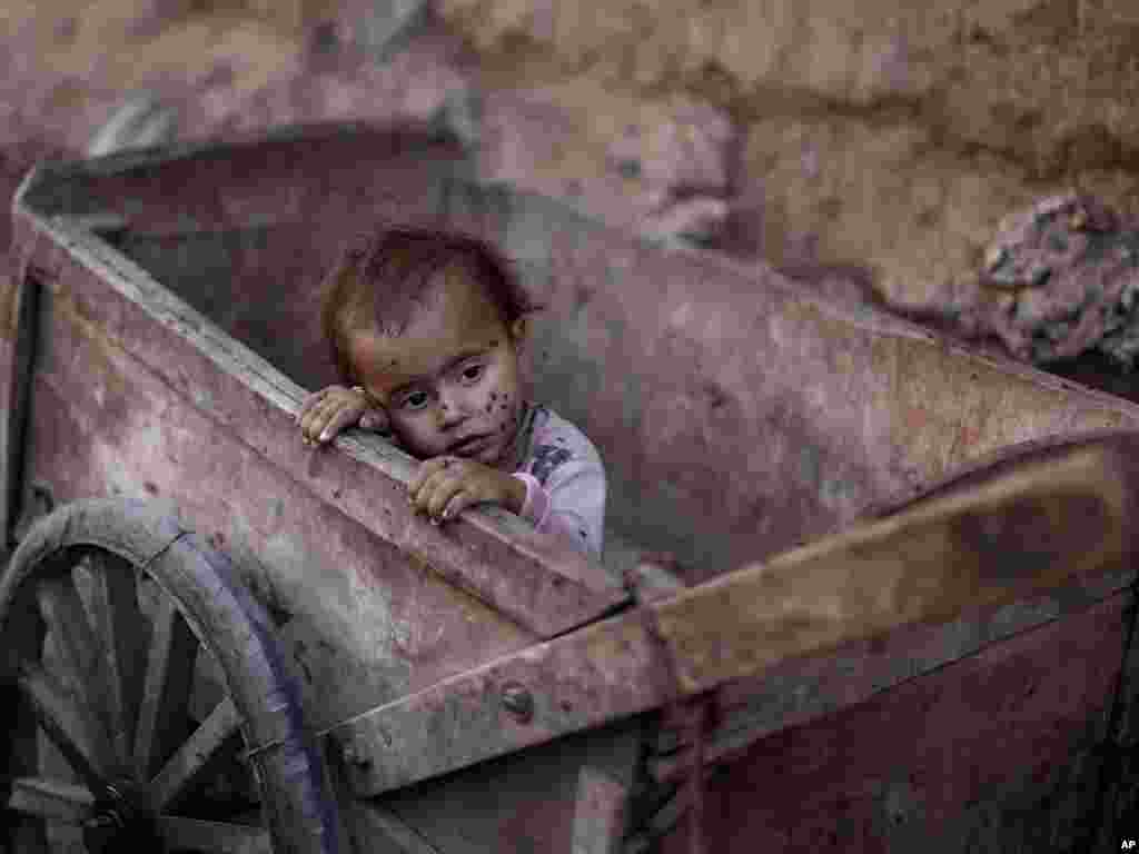 A Pakistani child, his face covered with flies, sits inside a wooden cart in an alley of a slum on the outskirts of Islamabad, Pakistan.Photo by Muhammed Muheisen for The AP