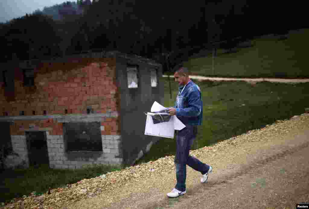 Surveyer Elvis Spijudic walks near houses destroyed during the 1992-95 war as he reads a map before interviews during Bosnia's first census in the village Krusev Do, near Srebrenica. (Reuters/Dado Ruvic)