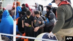 Migrants sit on a boat near the village of Kucukkuyu in western Turkey.