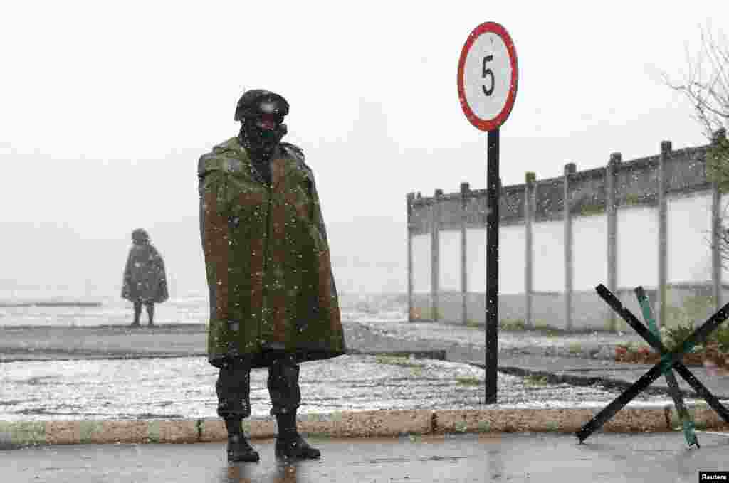 Armed men, believed to be Russian servicemen, stand guard outside a Ukrainian military base in Perevalnoye.