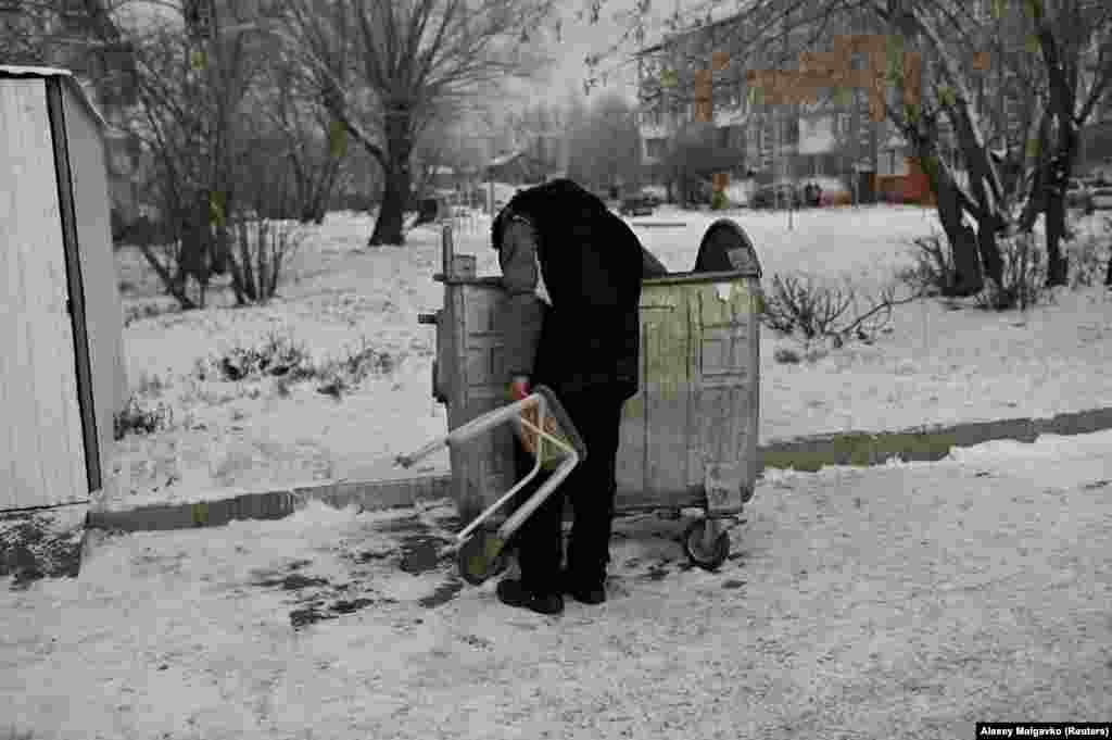 Bystrushkin, who is visually impaired and homeless, looks through a rubbish bin.