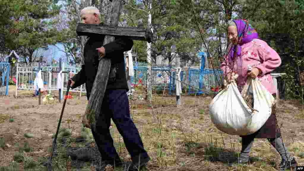 A man carries a cross on April 23, 2012, at a cemetery in the abandoned Belarusian village of Dovliady in the 10-kilometer exclusion zone around the Chornobyl nuclear reactor.