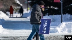 Pristalice bivšeg američkog predsjednika i predsjedničkog kandidata 2024. Donalda Trumpa nose plakate sa njegovim imenom, Indianoli, Iowa, 14. januara 2024. 