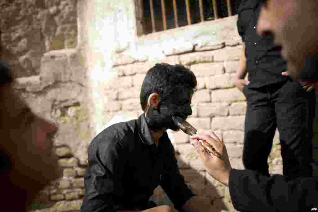 A boy playing the role of a genie has his face painted black.