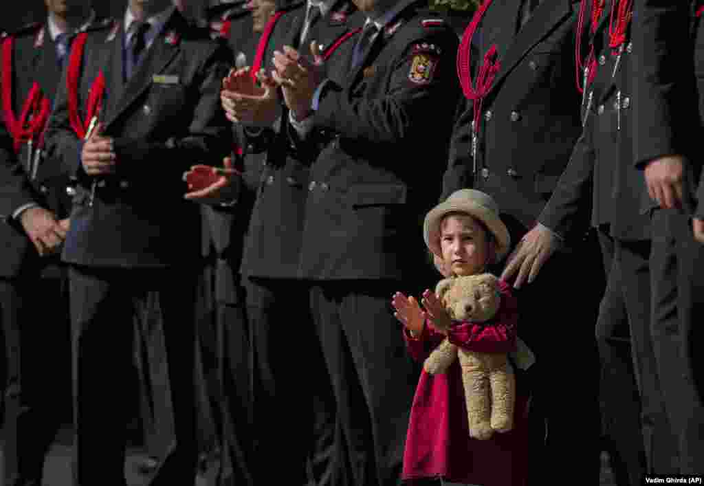 A girl holds a teddy bear while watching a military parade during festivities celebrating Romanian Firefighters Day in Bucharest on September 13. (AP/Vadim Ghirda)