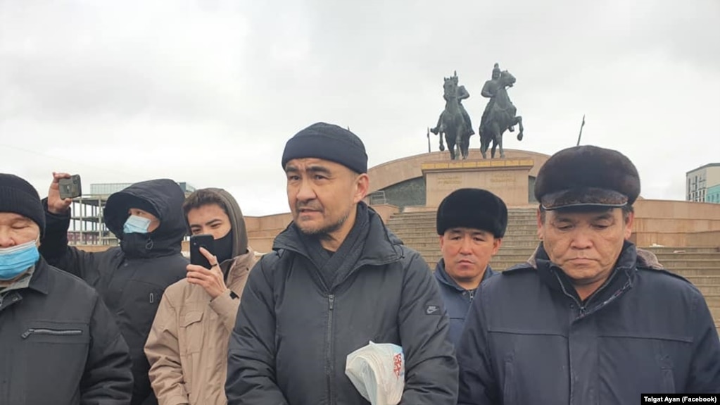 Макс Бокаев (в центре) стоит на площади в Атырау. 28 февраля 2021 года.