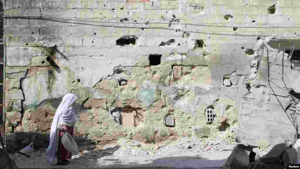 A Syrian woman walks past a building damaged by fighting in the Qaboun district of Damascus on July 31. (Reuters/Omar&nbsp; al-Khani)