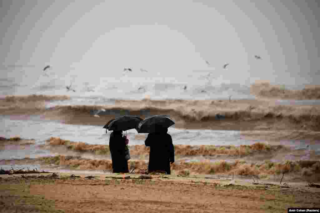 Ultra-Orthodox Jewish men hold umbrellas and look at the Mediterranean Sea as heavy rainfalls hit Ashdod in Israel. (Reuters/Amir Cohen)