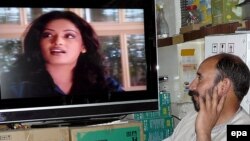 An Afghan man watches an Indian soap opera at his TV shop in Kabul. The Afghan culture minister said that female newsreaders should appear different from actresses in movies and soap operas.