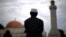 یو لمونځ کوونکی چې د کرونا ویروس له وېرې له جومات دباندې لمونځ کوي.