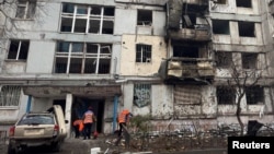 Коммуналдык кызматкерлер 2025-жылдын 23-ноябрында Украинанын Днепр шаарына дрон чабуулунан жабыркаган көп кабаттуу үйдүн жанын тазалап жатышат.