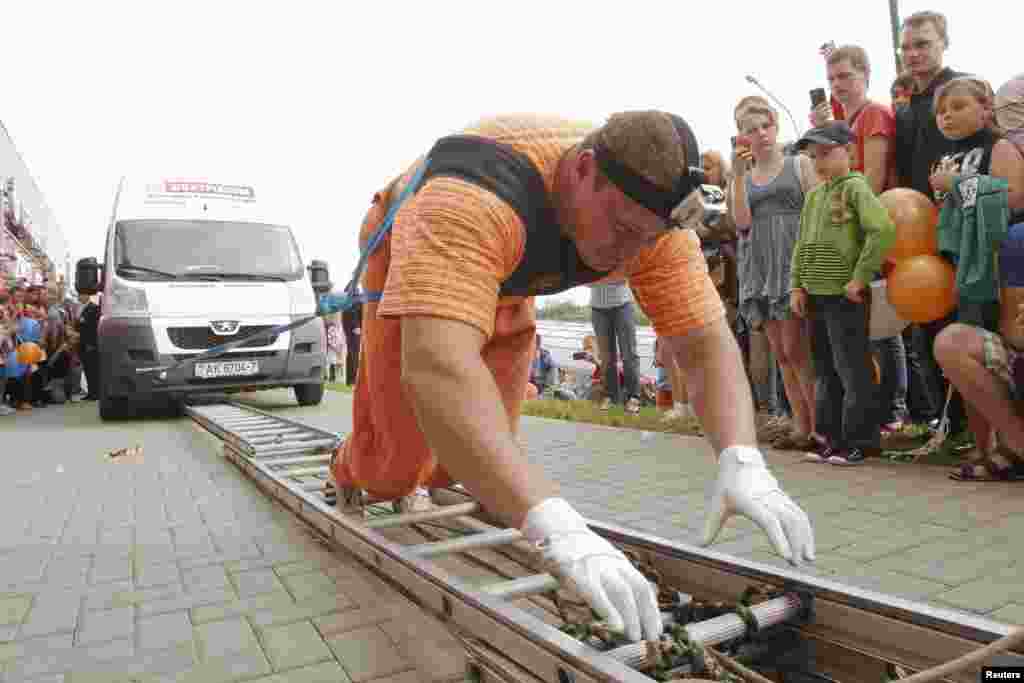 Belarusian strongman Kirill Shimko pulls seven buses, connected in a line and weighing about 15 tonnes, during the opening of a trade centre in Minsk on May 24. (Reuters/Vasily Fedosenko)