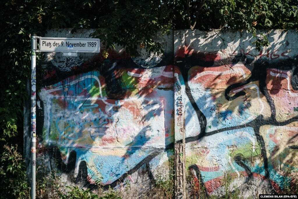 Një pjesë e ruajtur periferike e Murit të Berlinit qëndron pranë shenjës rrugore të një sheshi në kryeqytetin gjerman, që mban emrin "9 Nëntori 1989", sipas datës që shënon shembjen e strukturës së betontë. (12 gusht)  