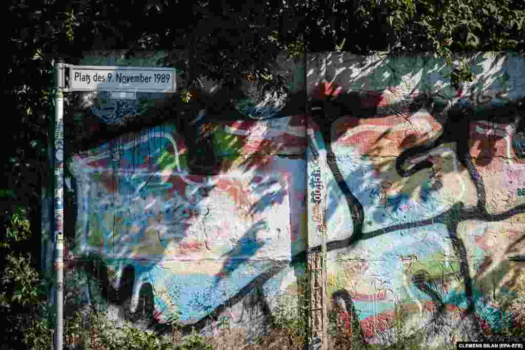 Një pjesë e ruajtur periferike e Murit të Berlinit qëndron pranë shenjës rrugore të një sheshi në kryeqytetin gjerman, që mban emrin &quot;9 Nëntori 1989&quot;, sipas datës që shënon shembjen e strukturës së betontë. (12 gusht) &nbsp;