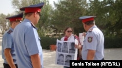 Гражданский активист Асель Нургазиева держит плакаты перед акиматом Жанаозена с фотографиями жителей, погибших во время событий в декабре 2011 года. Многомесячная забастовка нефтяников закончилась тем, что полицейские открыли огонь по демонстрантам. 29 августа 2012 года.