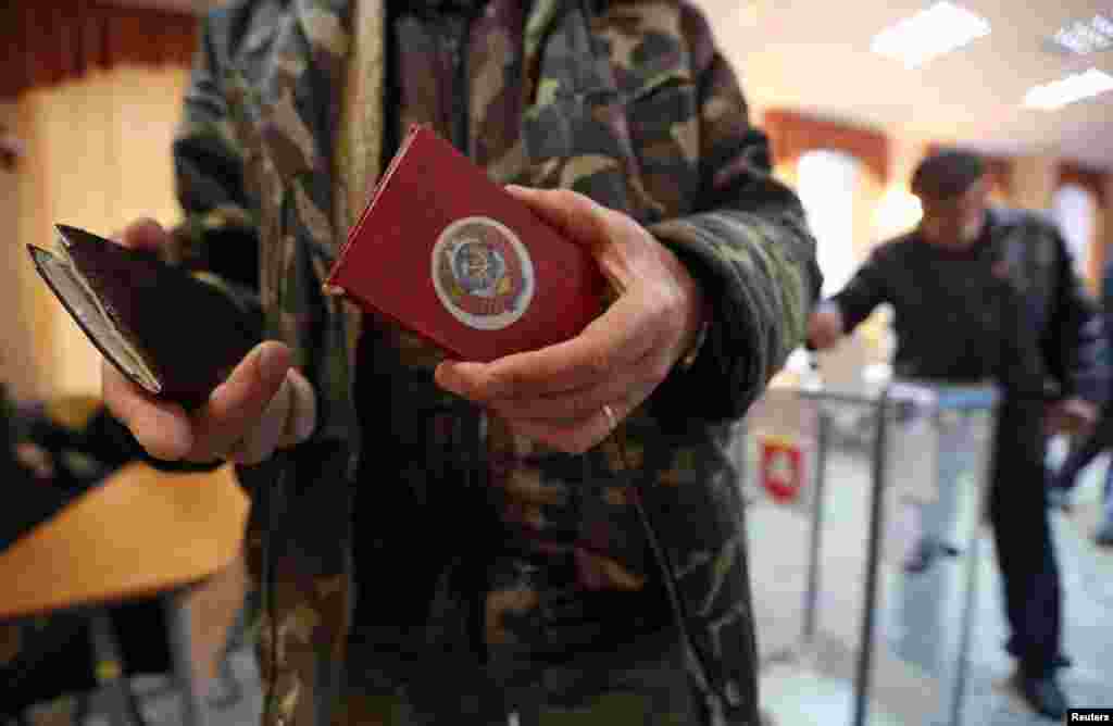 A man shows an identity document, emblazoned with the former USSR coat of arms, at a polling station in Simferopol.