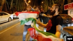 Иранцы с национальным флагом Ирана в руках празднуют достижение предварительного соглашения между Ираном и шестью лидирующим странами. 2 апреля 2015 года.