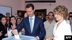  President Bashar al-Assad (center) and his wife Asma al-Assad (R) cast their votes at a polling station in Damascus on June 3. 