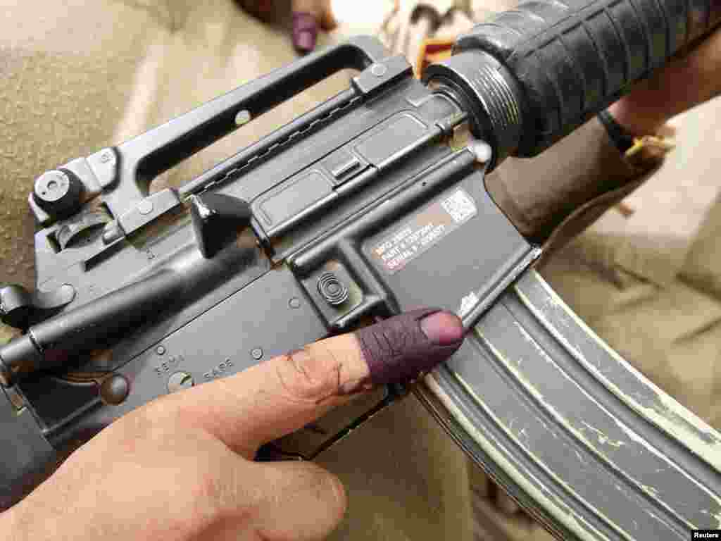 A member of Iraq's security forces displays his ink-stained finger after early voting in parliamentary polls. - Photo by Mohammed Ameen for Reuters