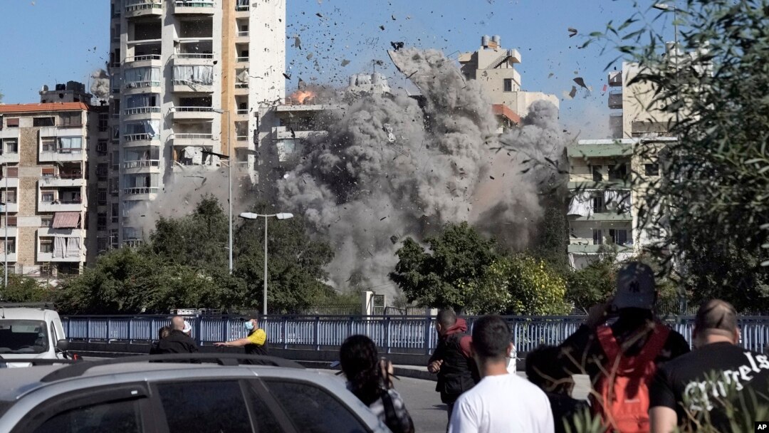 İnsanlar Beyrutda İsrailin hava hücumu nəticəsində vurulan binanın çökməsini izləyirlər.