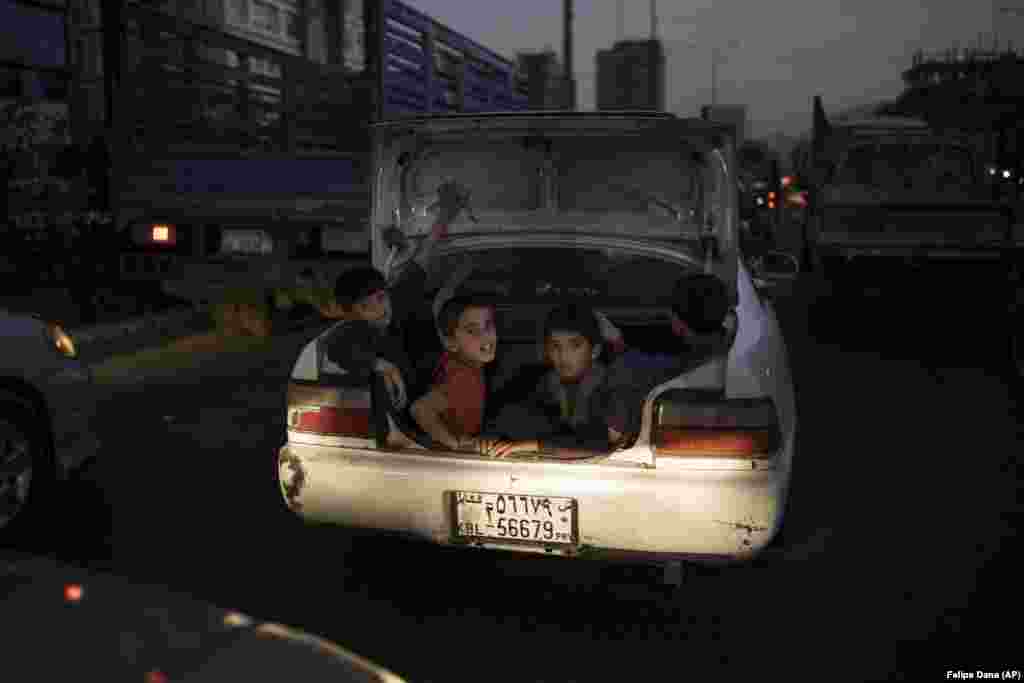 Afghan boys ride in the trunk of a car in Kabul.&nbsp;