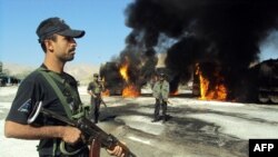 Pakistani policemen stand beside burning trucks that were carrying NATO fuel supplies after an attack by suspected Taliban militants in November.