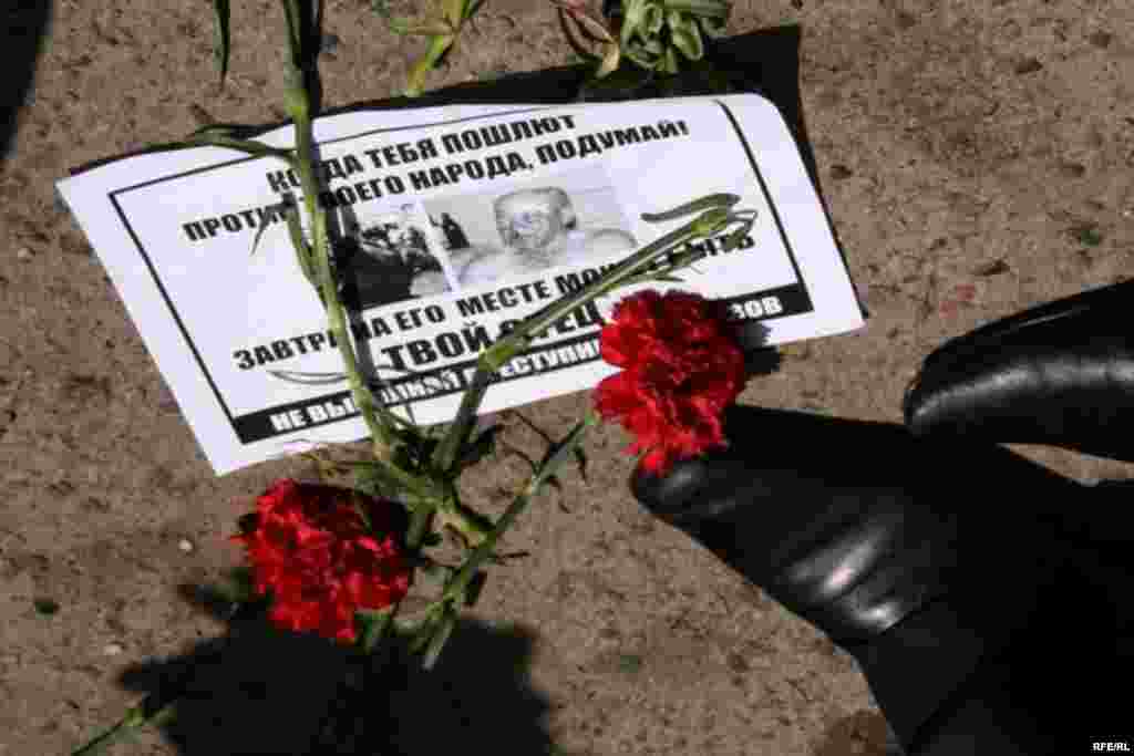 Листовка и гвоздики под ногами у полицейских, которые не дают пройти демонстрантам. Алматы, 1 мая 2010 года. 