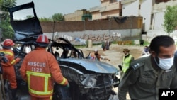 Volunteers search a badly damaged vehicle after a suicide bomb attack in Peshawar that killed three people on May 24.