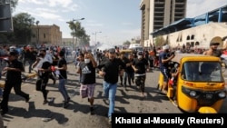 Demonstrators run during a protest over corruption, lack of jobs, and poor services in Baghdad on October 25.