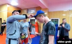 A screen-grab shows Georgy Makaryev handing out baseball caps and poetry to recruits in his NADO youth organization in the Russia-backed, separatist-held Luhansk region.