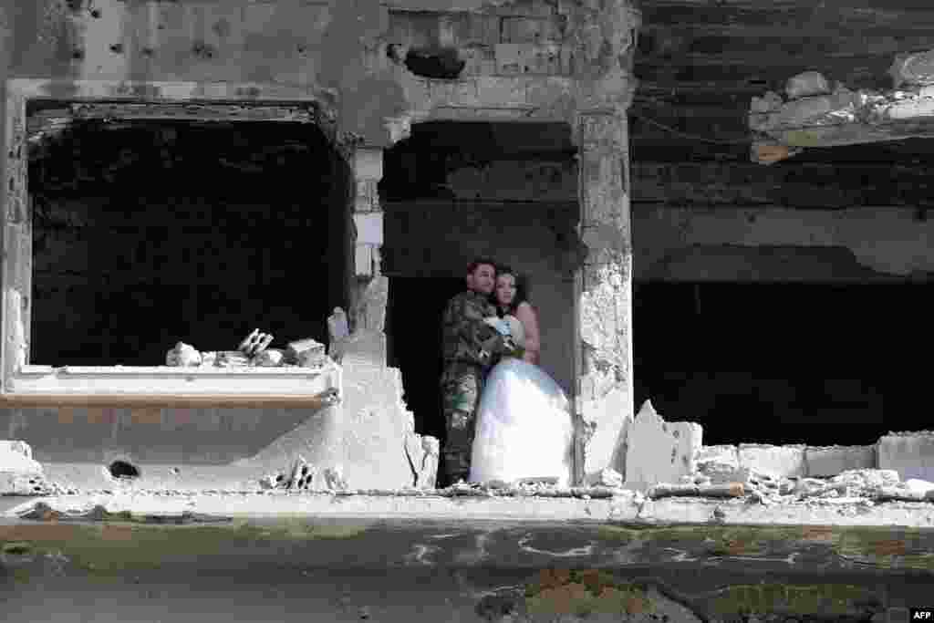 A newly-wed Syrian couple pose for a wedding picture amid heavily damaged buildings in the war-ravaged city of Homs. (AFP/Joseph Eid)