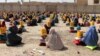 Afghans sit on the ground after they receiving ration aid in Kandahar last month. 