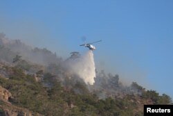 Një helikopter zjarrfikës hedh ujë ndërsa një zjarr i madh po digjet pranë Ierapetrës, në ishullin e Kretës, Greqi, 3 korrik.