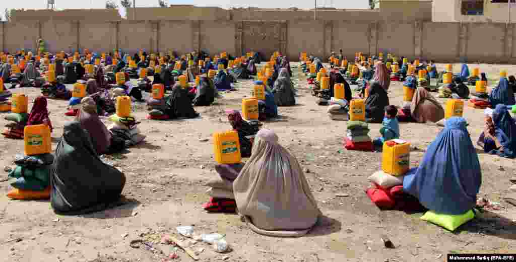 Afghans sit on the ground after they received ration aid in Kandahar. (efe-EPA/Muhammad Sadiq)